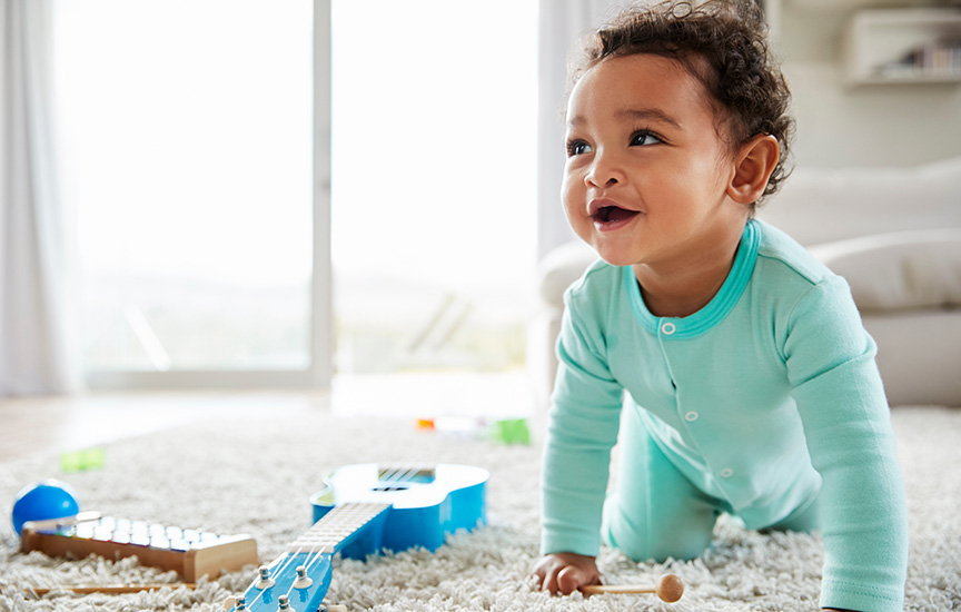 A baby boy happily playing with colorful toys on the floor, surrounded by a cheerful atmosphere.
